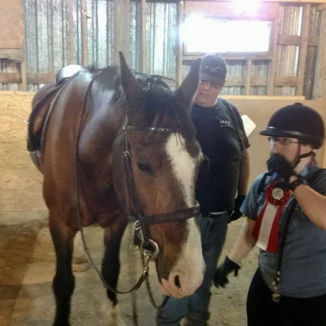 Sally assisting a volunteer with tacking up her horse.